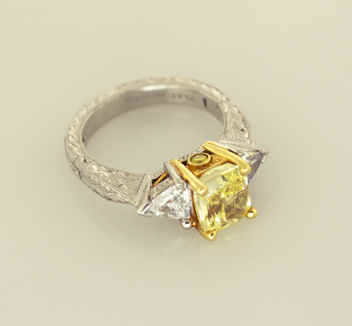 Fancy intense  yellow radiant cut diamond set with 2 trillians in Plat & 18KT  