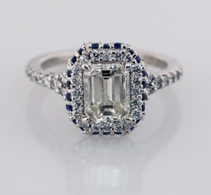 Emerald cut diamond with sapphire and diamond surround engagement ring